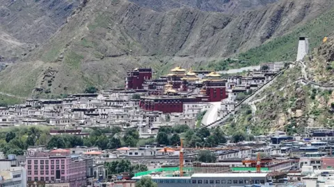 Getty Images Buildings and a monastery in the town of Shigatse, against a backdrop of green mountains