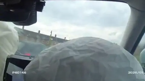 A body camera view of the inside of a vehicle which has deployed it's airbags after crashing