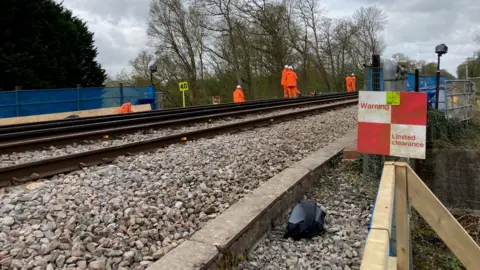 BBC/Piers Hopkirk Network Rail staff in hi-vis clothing stand on railway lines at the Bough Beach embankment