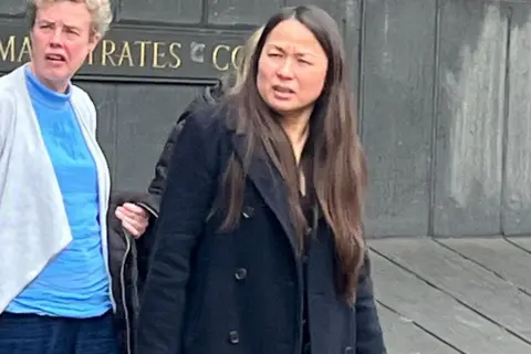 PA Media Long-haired woman in navy peacoat next to a woman in blue top and light cardigan