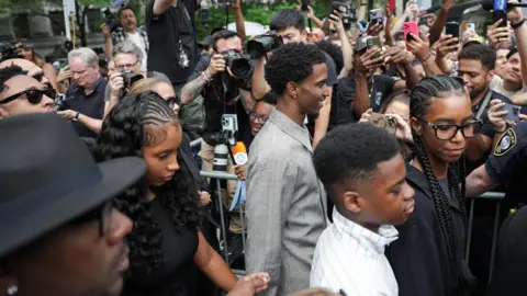 Reuters Three people walk through a crowd of cameras 