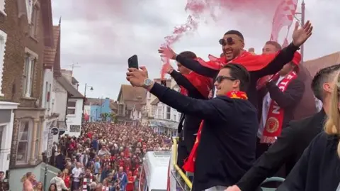 Jacob Panons/BBC A group of people taking a selfie on an open-top bus