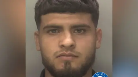 A young bearded man looks towards the camera