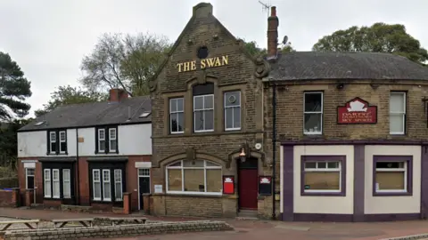 Google An outside view of The Swan pub. Three benches can be seen outside.
