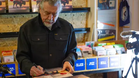 TGP Wilson Robert Plant signs a copy of his album "Saving Grace" in Cardiff's Spillers Records