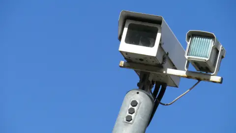 A CCTV camera against a bright blue sky.