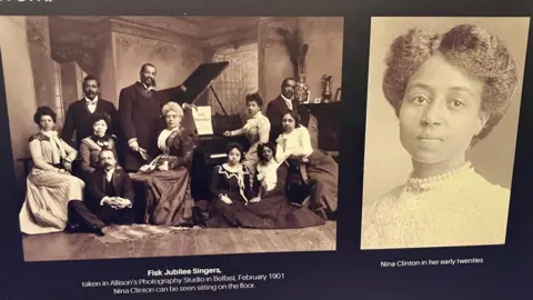 A picture on one of the exhibits is of Nina Clinton in a white dress and pearl necklace is beside a group photo of the Fisk Jubilee Singers.