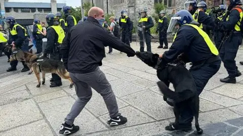 Getty Images A police dog bites a man's sleeve during disorder in Plymouth