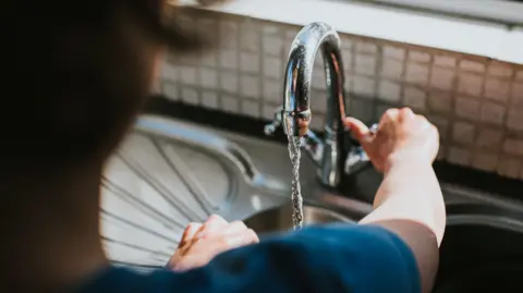 Getty Images Person turning kitchen tap on