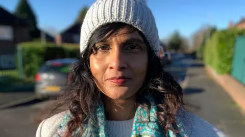 Ramona Hirschi, who is outside in a road in the city, wearing a jumper, scarf and bobble hat