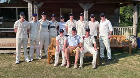 Dexter Coad An older man surrounded by people in cricket gear.