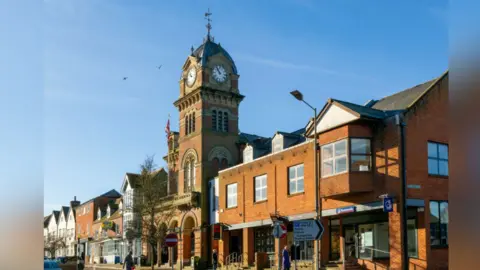 Getty Images A picture of Hungerford Town Hall, a Victorian era building with a clock tower, and shops surrounding it in High Street, Hungerford.