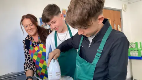 A teacher helps two teenage boys