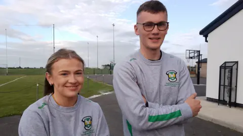 Aoife McIlvar with Ronan Close. They're wearing their grey uniform with their club logo.