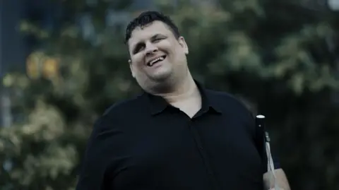 Rebecca Parker A man wearing a black shirt, carrying a white cane