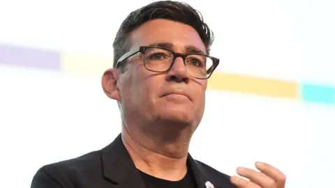 PA Media Andy Burnham, who has dark hair and glasses, in a close-up shot. 