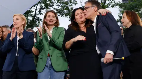     LUDOVIC MARIN/AFP Member of the French Parliament "La France Insoumise" Group (LFI) Raquel Garrido (2nd R) embraces the French Socialist Party (PS) First Secretary Olivier Faure (R) as National Secretary for The Ecolog formerly known as Europe-Ecologie-Les Verts (EELV) Marine Tondelier (2nd L) and French MP for La France Insoumise (LFI) and member of the left coalition NUPES Clémentine Autain (L) applauded