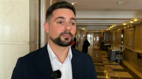 Joe Harris stands in a marble lobby at the Liberal Democrat conference venue in Brighton.