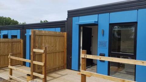 SoloHaus modular homes, which have flat roofs, are painted blue and have wooden fences and decking