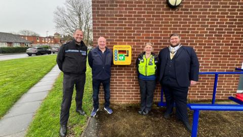 Two police officers, Ewan Patrick and the town mayor stand beside the defibrillator