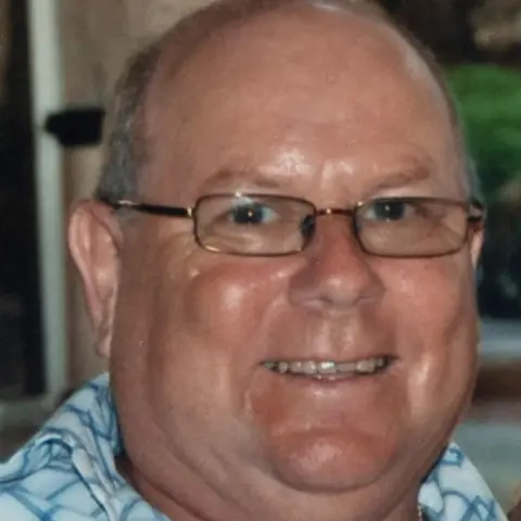 SWNS David Pethig who has grey hair and is wearing rectangular glasses and a shirt