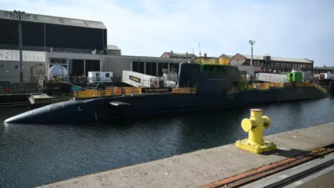 HMS Agamemnon nuclear submarine at the BAE Systems factory, Barrow-in-Furness, Cumbria. There is an industrial port on the other side of the water, which has the submarine in it. 