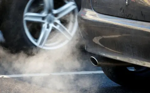 The picture shows a plume of white fumes coming out of a car's exhaust pipe