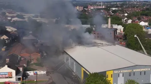 Phil Ireland Smoke can be seen billowing from the building in this photo, with firefighters tackling the blaze with hose reel jets.