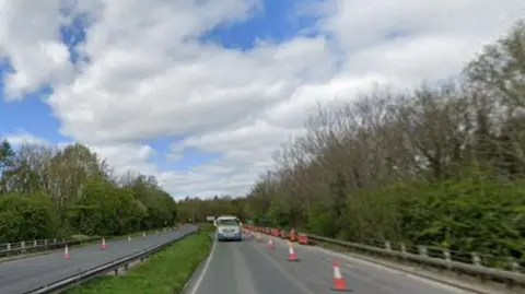 Road with a lorry driving on it with trees either side of the carriageway