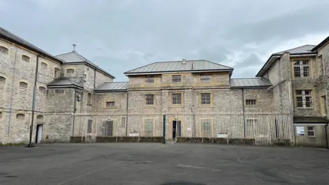 Exterior of Shepton Mallet Prison, with a grey cloudy sky in the background