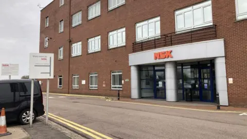 A red brick building with a sign saying NSK