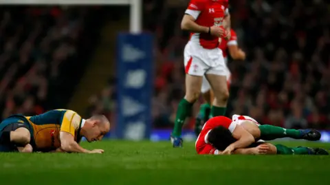 Stu Forster/Getty Images Jamie Roberts lies injured on a rugby pitch while wearing the red of Wales. Australian captain Stirling Mortlock lies on the grass to Jamie's left.