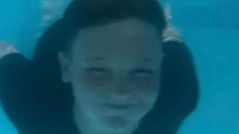 Family photo Freddie swimming underwater and smiling at the camera