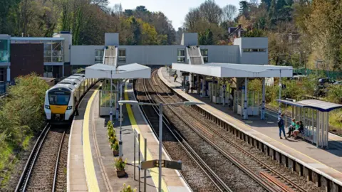 An aerial shot of Sevenoaks Station. There is a train at a platform and people waiting on another. 