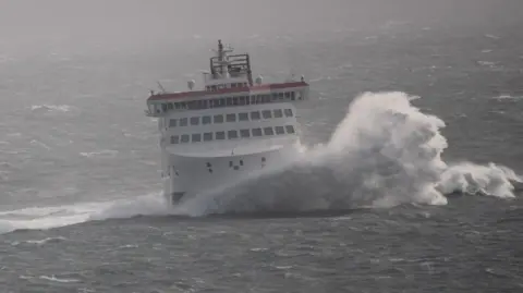 The Manxman - a large white ferry - in rough seas with a wave breaking against the bow.