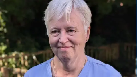 Close-up shot of Christina Peter in a nurse's uniform. She is smiling at the camera.