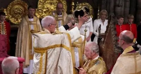 PA Media Justin Welby, the former Archbishop of Canterbury, stands in front of King Charles to place the crown on his head, during his coronation ceremony at Westminster Abbey