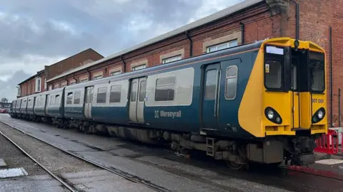 PA Media Three-carriage blue and white electric train with a yellow from end pictured in a siding