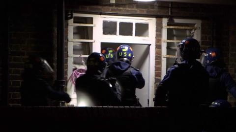 Police officers enter property in protective gear