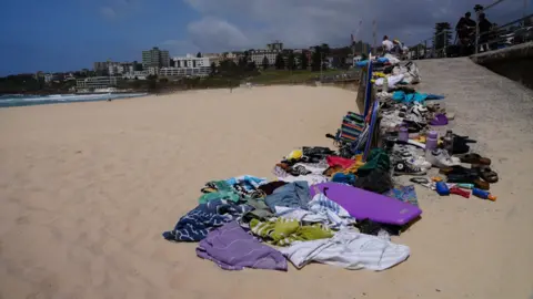 BBC/Isabelle Rodd A pile of belongings on the beach at Bondi