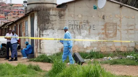 Reuters A man from the police forensics team wheeling a black suitcase and wearing blue protective gear at the scene of the attack 