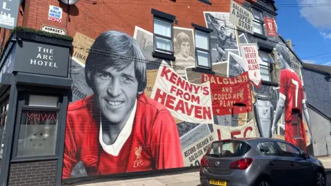 BBC/Angela Ferguson A large colourful mural features Sir Kenny Dalgleish and a selection of newspaper cuttings and photos.