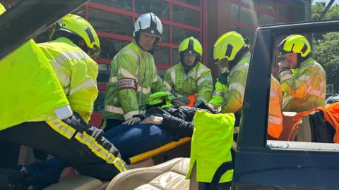 Firefighters extricating a casualty from a car on a stretcher