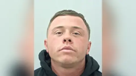 Lancashire Police Police custody shot of Paddy Nolan. He has short brown hair and is wearing a black hoodie.