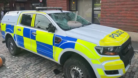 PA A vandalised police vehicle with an object thrown at its windscreen