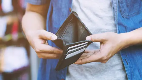 A man is opening a wallet to reveal it is empty