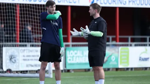 Chelmsford City Football Club Two goalkeepers on a pitch talking to each other