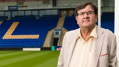 Professor Steven Broomhead, the outgoing chief executive of Warrington Borough Council. He is standing on the pitch at Warrington Wolves' stadium.