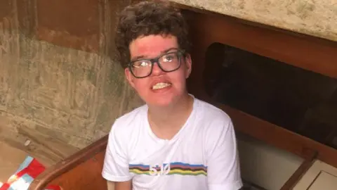 Family photo of Fraser. He is wearing a white T-shirt and glasses