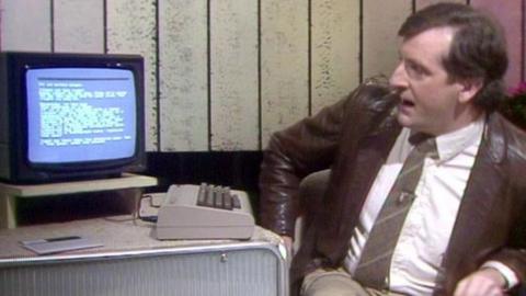 Douglas Adams sitting next to a computer.